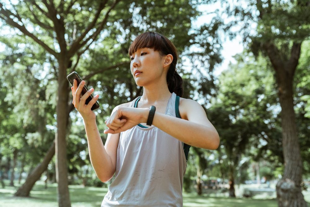 Nő sétál a szabadban, telefonján méri a lépésszámát