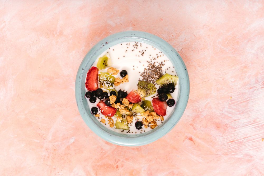 Gyümölccsel és fahéjjal díszített natúr joghurt egy tálban